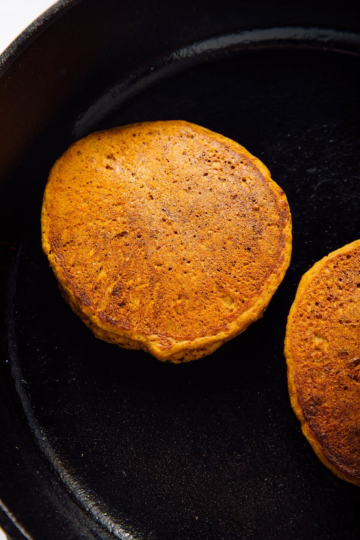 pumpkin oat pancakes cooked in skillet