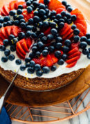 slicing lemon almond cake with berries on top-4