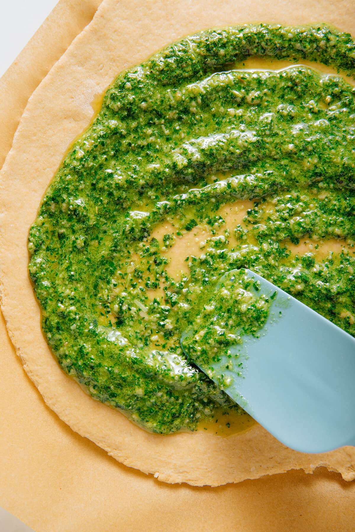 spreading pesto on pizza